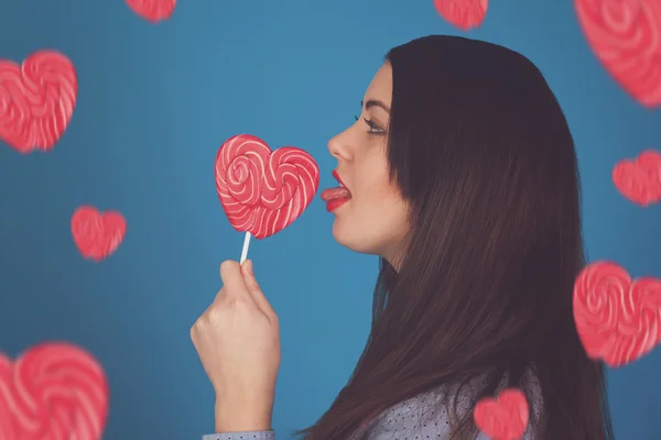 Woman is tasting a pink lollipop — Stock Photo, Image