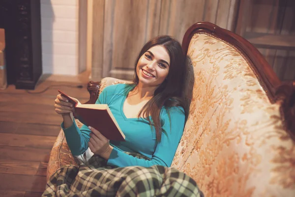 Auf dem Sofa lächelnde Frau mit rotem Buch — Stockfoto