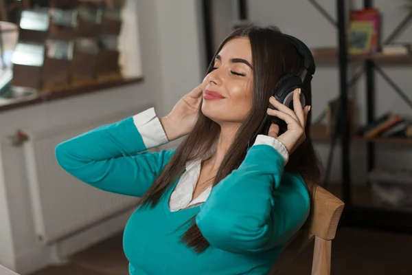 Vrouw met hoofdtelefoon op stoel — Stockfoto