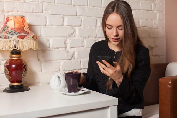 Vrouw met thee en smartphone — Stockfoto