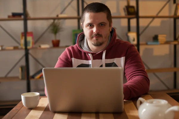 Pohár, laptop a muž s kapucí — Stock fotografie