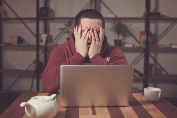 Homem cansado com laptop — Fotografia de Stock