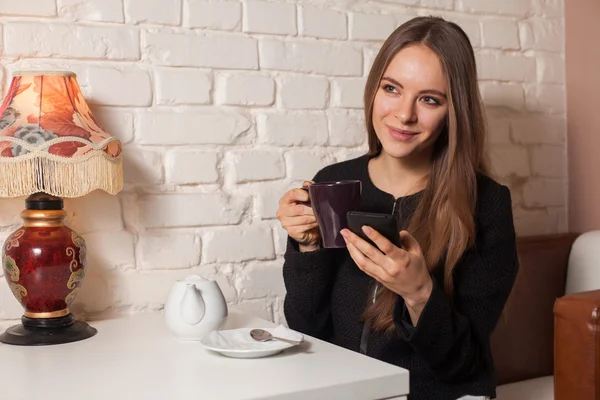 Woman with tea and smartphone — Stock Photo, Image