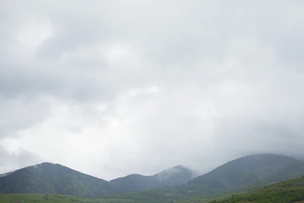 Montañas y niebla bajo el cielo gris — Foto de Stock