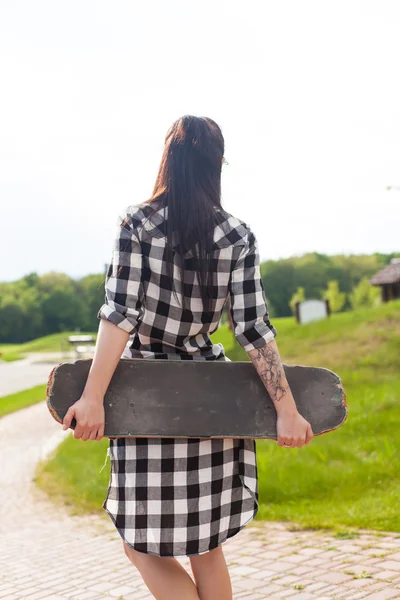 A mulher segura um skate — Fotografia de Stock