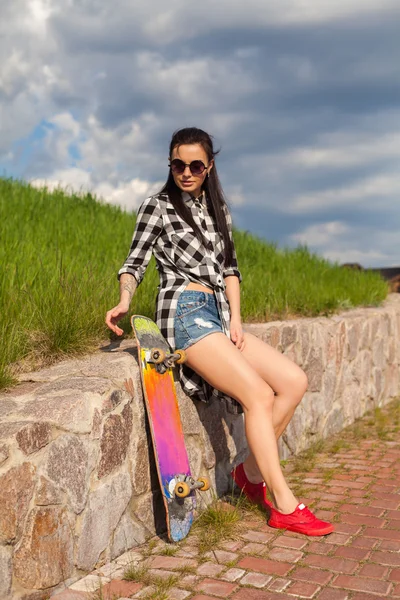 A mulher está de pé com um skate — Fotografia de Stock