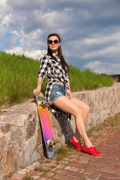 De vrouw staat met een skate — Stockfoto