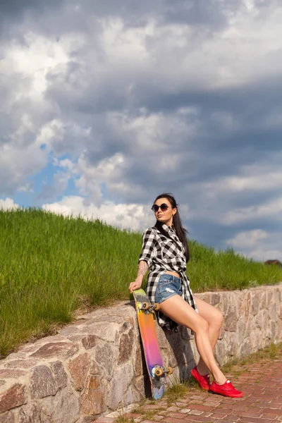 A mulher está de pé com um skate — Fotografia de Stock