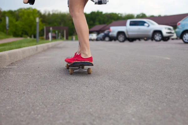 No fundo da grama verde a mulher com saco em sapatos rosa está patinando — Fotografia de Stock