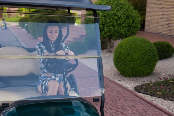 La mujer está en un carrito de golf. — Foto de Stock