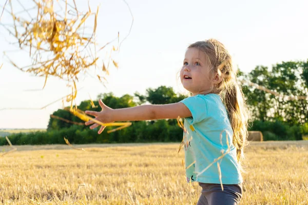 Menina brincando com grama de trigo no campo — Fotografia de Stock