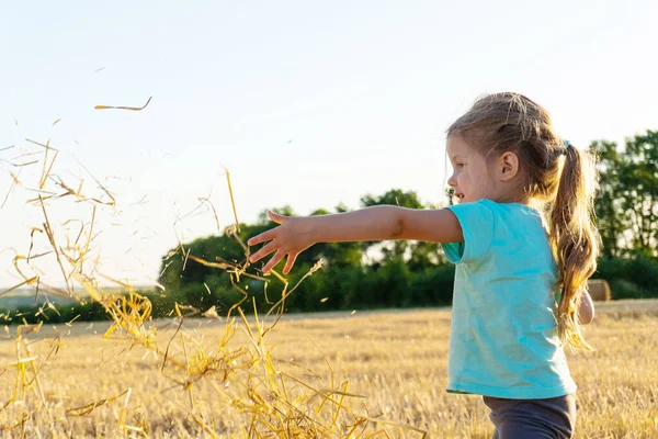 Menina brincando com grama de trigo no campo — Fotografia de Stock