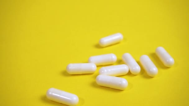 Cápsulas de píldoras blancas en el fondo amarillo — Vídeos de Stock