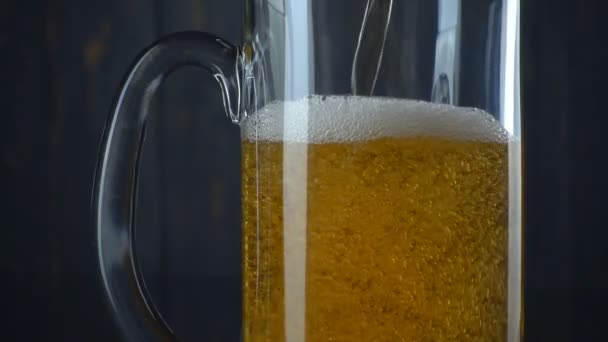Bier in Glas über dunklem Holzgrund gießen. Zeitlupe — Stockvideo
