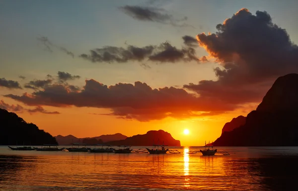 Barcos filippino tradicionales en la bahía de El Nido con luces de puesta de sol . — Foto de Stock