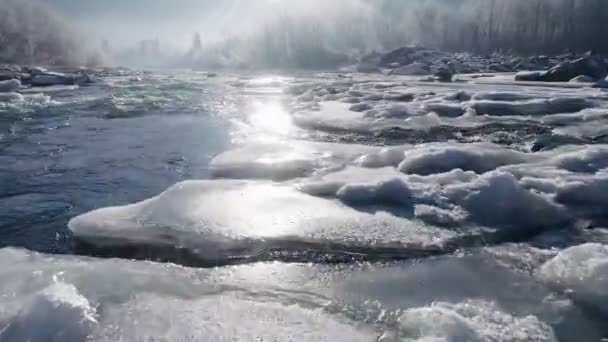Foto aérea de río de montaña con islas de hielo. Los rayos del sol naciente se reflejan en la corriente de agua hirviendo. Paisaje invernal con río, hielo y árboles — Vídeos de Stock