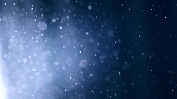 Sněhové částice létají ve vzduchu. Kouzelně modré třpytivé částice s čočkou bokeh. Sněhové vločky ve větru. Nádherná zima Nový rok pozadí — Stock video