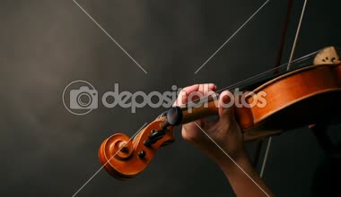 Kadın koyu arka plan üzerinde keman çalıyor. Slowmotion