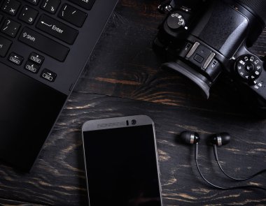 Dizüstü bilgisayar, akıllı telefon, fotoğraf makinesi ve kulaklık üzerinde ahşap backgrou