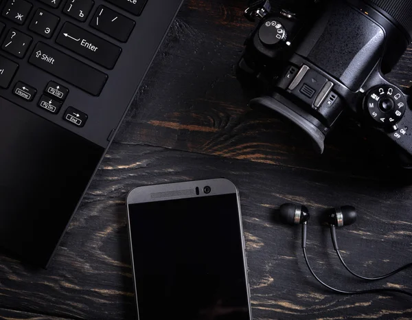 Laptop, telefone inteligente, câmera fotográfica e fone de ouvido em backgrou de madeira — Fotografia de Stock