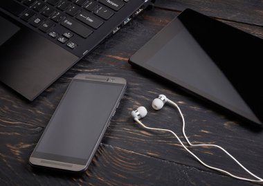 Dizüstü bilgisayar, akıllı telefon, tablet pc ve ahşap arka plan üzerinde kulaklık