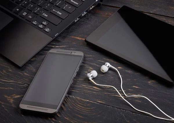 Laptop, telefone inteligente, tablet pc e fone de ouvido em fundo de madeira — Fotografia de Stock