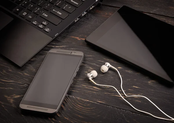 Laptop, telefone inteligente, tablet pc e fone de ouvido em fundo de madeira — Fotografia de Stock