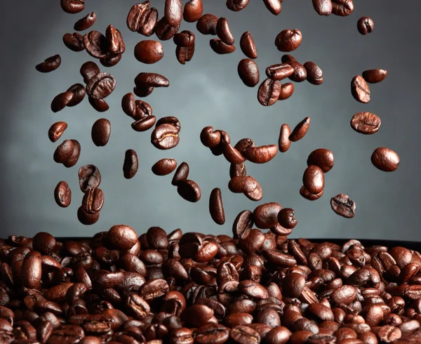 Flying coffee beans over dark background — Stock Photo, Image