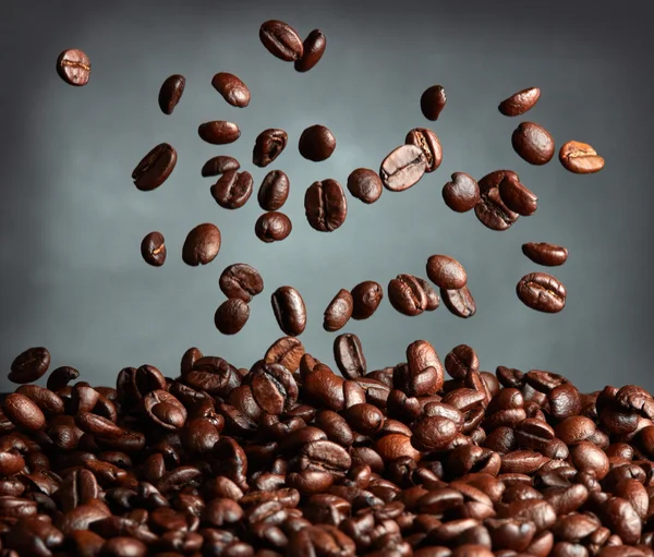 Flying coffee beans over dark background — Stock Photo, Image