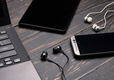 Dizüstü bilgisayar, akıllı telefon, tablet pc ve ahşap arka plan üzerinde kulaklık
