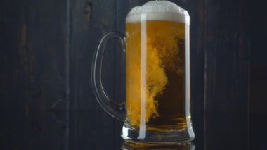 Bira bardağına koyu ahşap arka plan üzerinde dökme. Ağır çekim