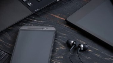 Dizüstü bilgisayar, akıllı telefon, fotoğraf makinesi ve ahşap arka plan üzerinde kulaklık