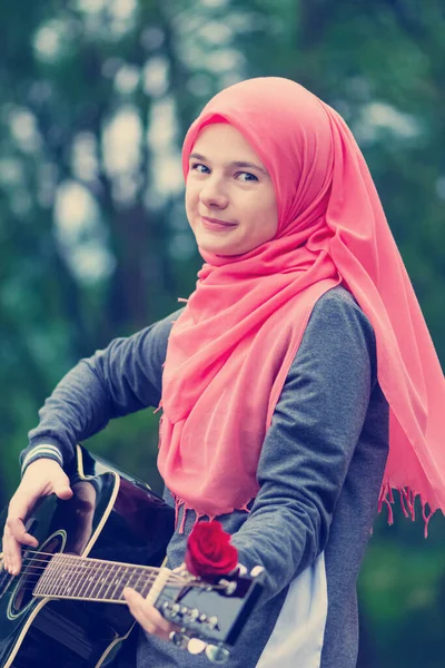 Портрет счастливой мусульманской девушки, пытающейся играть на гитаре — стоковое фото