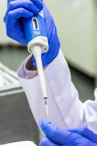 Naukowiec umieszczający próbkę w probówce podczas noszenia rękawic ochronnych — Zdjęcie stockowe