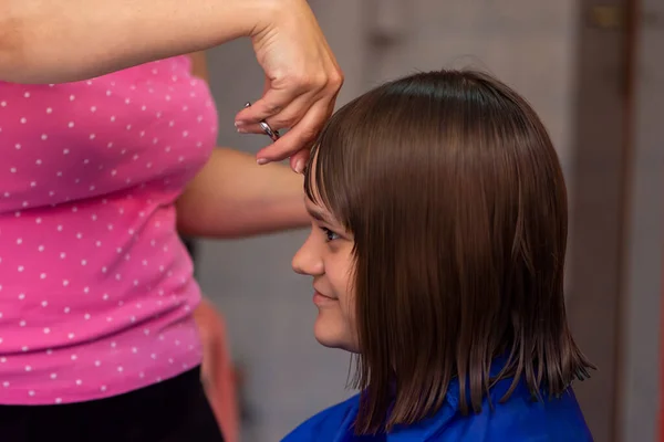 Professional female hairdresser cutting girls hair in salon — Stock Photo, Image