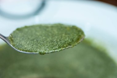 Kaşıkta ısırgan otu kremalı yeşil çorba. Doğal ve sağlıklı bitkiler, vejetaryen yiyecekler. Ispanak mı, naneli mi?