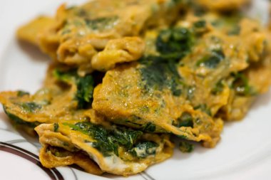 Beyaz tabakta servis edilen ısırgan otlu omlet. Kahvaltıda yabani otları kapatıyoruz.