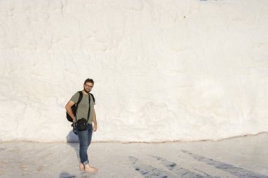 Pamukkale 'de havuza çıplak ayakla giren mutlu turist. Arkasında kadın ayakkabıları tutan çocuk. Türkiye 'de yaz turizmi, ünlü turizm beldesi