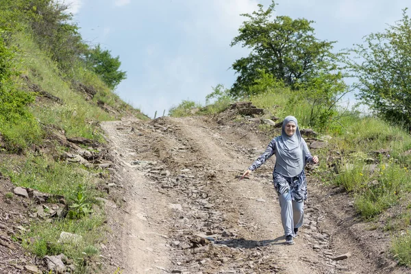 Młoda muzułmanka w stroju sportowym spacerująca samotnie po wiejskiej drodze górskiej — Zdjęcie stockowe