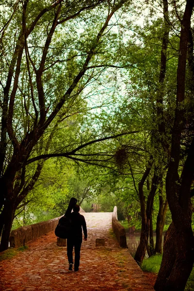 Jovem carrega saco de guitarra enquanto caminha pela floresta — Fotografia de Stock