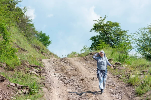 Young muslim girl wearing sport clothes walking alone on the rural mountain road