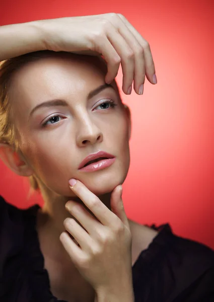 Ung blond kvinna poserar över röd bakgrund, skönhet koncept — Stockfoto