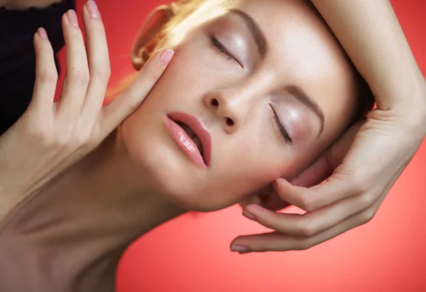 Mujer rubia joven posando sobre fondo rojo, concepto de belleza — Foto de Stock