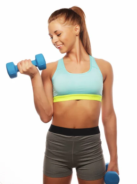 Jonge vrouw in sportuitrusting oefenen met de hand gewichten over witte achtergrond — Stockfoto
