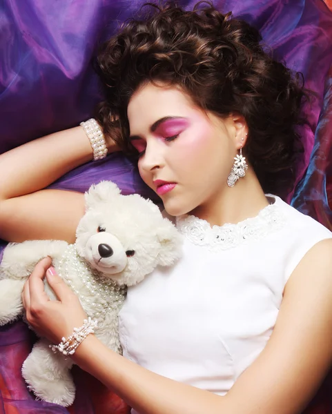 Woman lay on organza with teddy bear — Stock Photo, Image