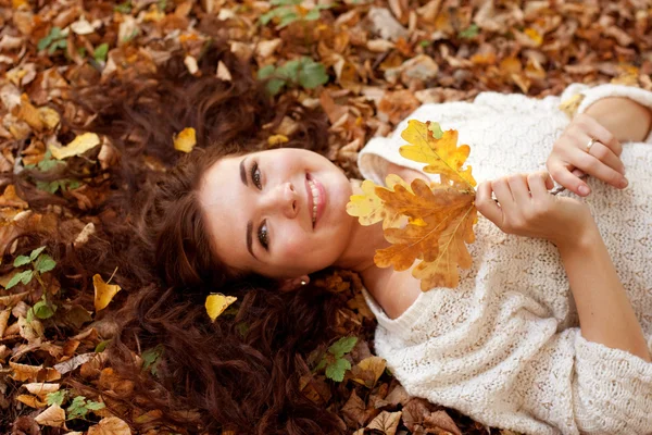 Femme allongée sur des feuilles d'automne, portrait extérieur — Photo