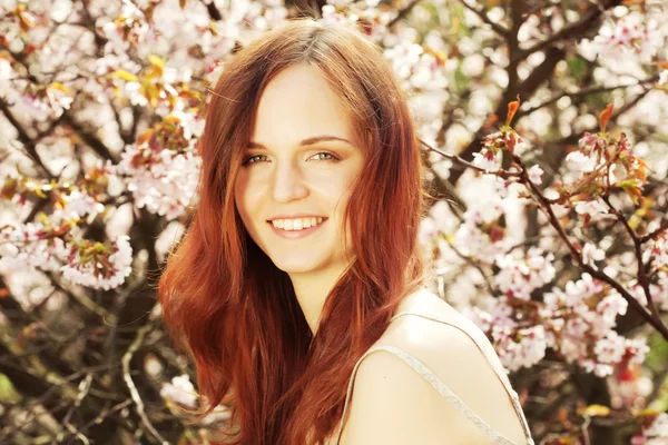 Heureuse jeune femme dans le jardin de fleurs de printemps — Photo