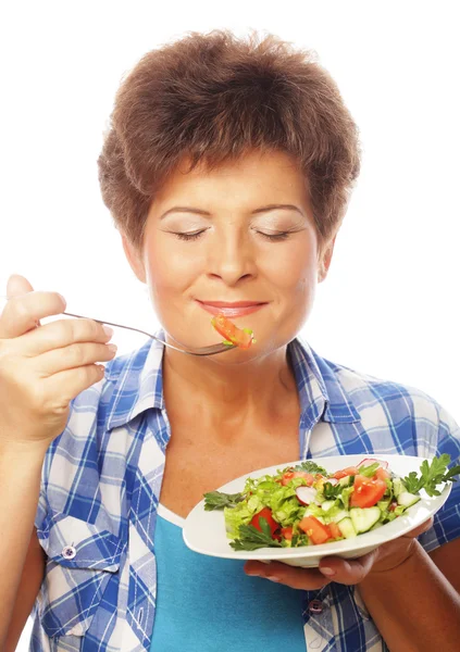 Зрелая улыбающаяся женщина ест салат — стоковое фото