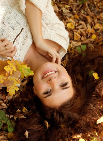 Femme allongée sur des feuilles d'automne, portrait extérieur — Photo