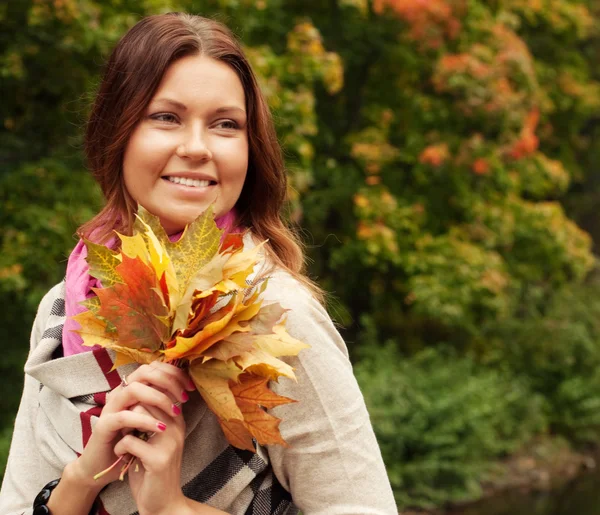 Jonge vrouw met herfstbladeren in park — Stockfoto